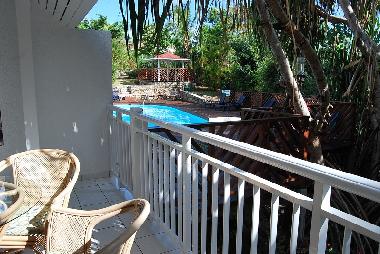 Depuis la terrasse couverte, la vue sur la piscine et le jardin